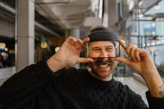 Smiling man holding smartphone appearing through the screen