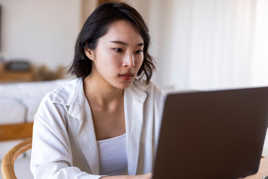 Woman intently working on laptop in bright room.