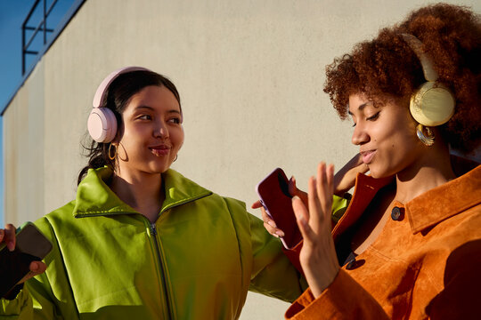 Two women listening to music with headphones and smartphone