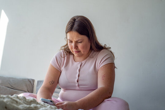 Young white woman looking at phone at home