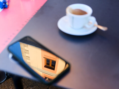 Smartphone screen reflecting building architecture on table