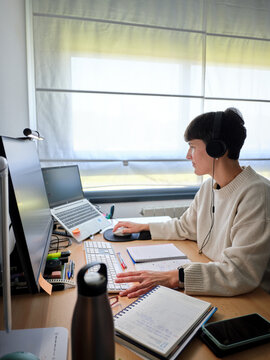 Woman working remotely at home with computer and headphones