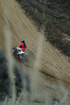 Man riding an orange motocross bike on a mountain track.