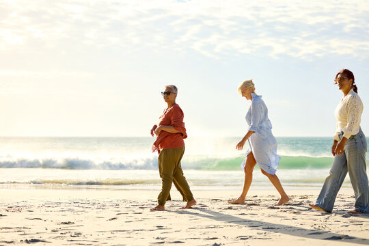 Three Women Walk Along the Beach During Sunset