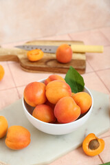 Boards and bowl with fresh apricots on pink tile table