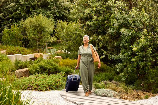Woman Walks and carrie Suitcase in Garden Area