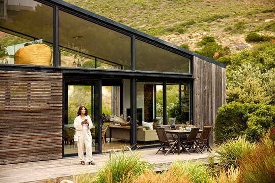 Woman using phone by Modern House in Nature