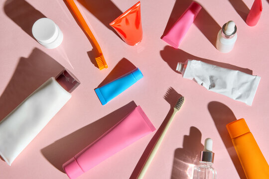 Colorful flat lay of oral care and beauty products on pink background