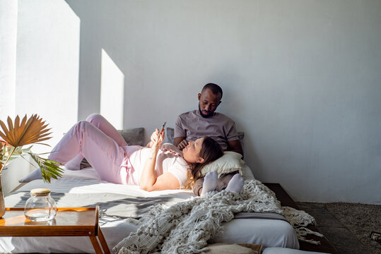 Interracial couple relaxing at home on a bed