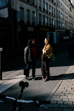 Friends chatting while standing on a sidewalk in the streets of Paris