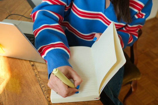 Writing notes in notebook at desk workspace