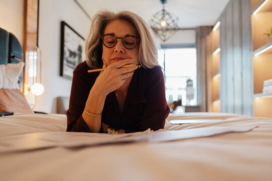 Contemplating financial decisions while reviewing paperwork at home