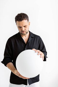 Man holds sphere in minimalist setting
