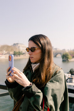 Tourist taking photos with a smartphone along the Seine River in Paris