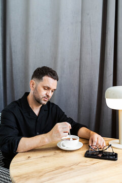 A man stirs his tea with a spoon.