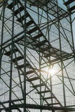 Metal watchtower stairs with sunlight and geometric structure