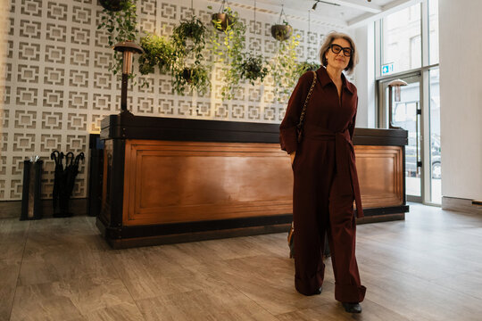 Stylish Senior woman traveling arriving at luxury hotel lobby