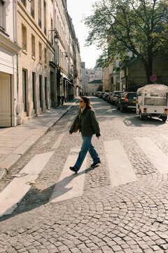 Female tourist walking on a crosswalk while strolling through Paris