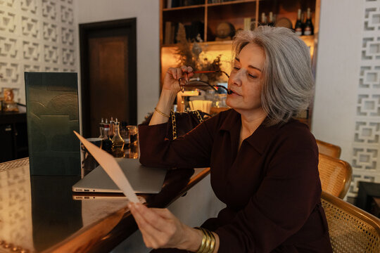 Senior woman reading menu having drinks at elegant restaurant