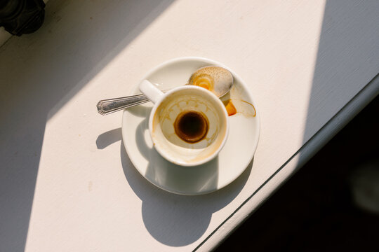 Used empty coffee cup resting on a white table under bright sunlight