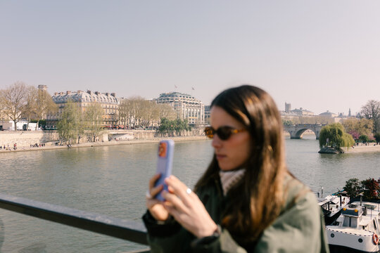 Blurred tourist using a smartphone to photograph the Seine River