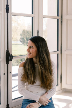 Young woman sitting on a window ledge at a rural hotel in France