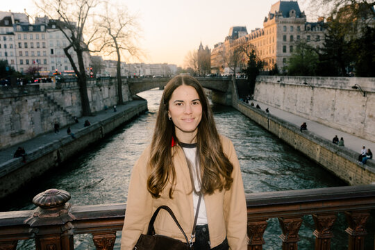 Female tourist looking at camera posing on a bridge over Siene River