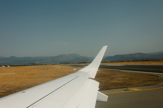 Airplane wing on runway with mountains in background