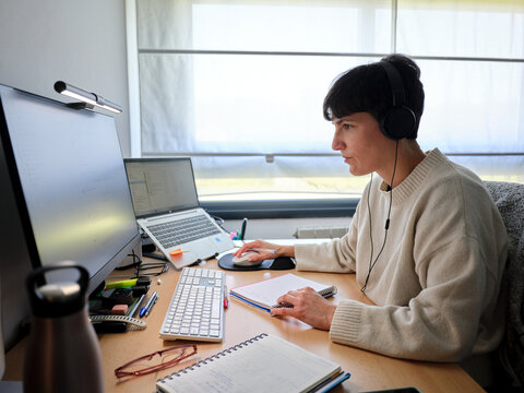 Woman working remotely at home office using computer