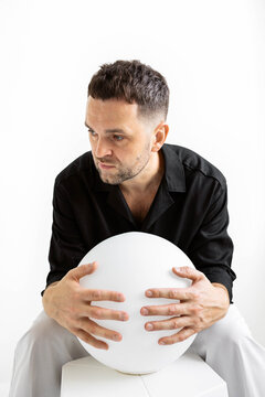 Man holds sphere in minimalist setting