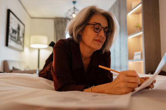 Retired Senior woman working on documents in bed