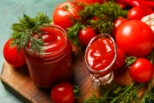 Jar and gravy boat with tasty ketchup and fresh vegetables on table, closeup