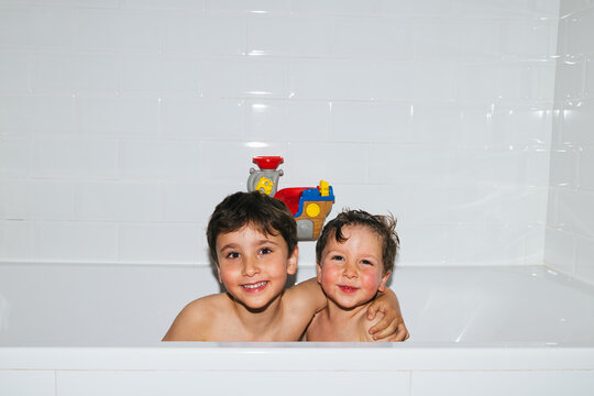 Children brothers enjoying bath time together splashing water