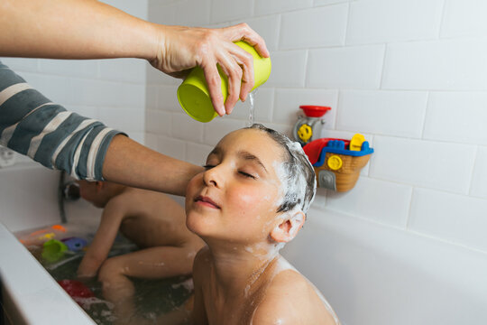 Happy children playing and washing hair during fun bath time