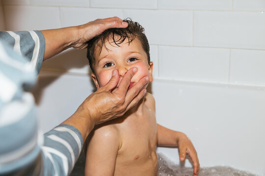 Parent washing child's hair during joyful bath time experience