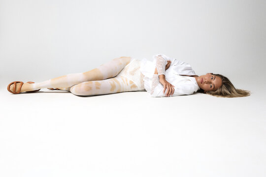 Woman lying on floor in minimal studio setting with soft neutral tones
