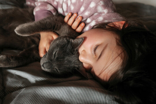 Child and Cat Resting Together in a Cozy Bedroom