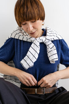 The woman straightens her shirt.