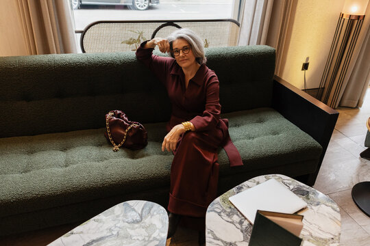 Elegant Senior woman relaxing on green sofa indoors