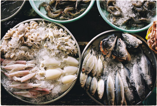 Fresh seafood displayed on ice in a market with various types of Fish