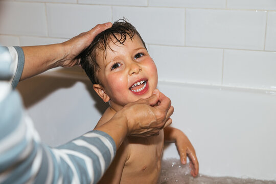 Child enjoying bath time with parent washing hair