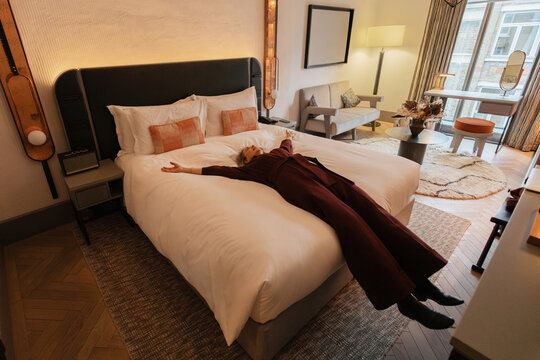 Senior woman relaxing getting comfort in luxurious hotel room bed