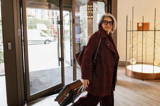 Traveler arriving at hotel lobby pulling luggage