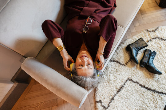 Senior woman enjoying music and relaxation on couch