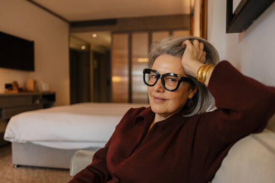 Confident senior woman wearing stylish glasses relaxing in hotel