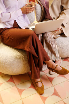 Women in business collaborating with laptop on modern armchair