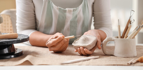Female sculptor with tool carving clay figure in workshop © Pixel-Shot