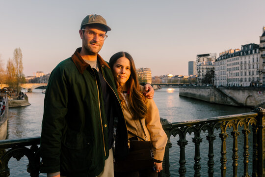 Couple of travelers posing over the Seine River in Paris during sunset