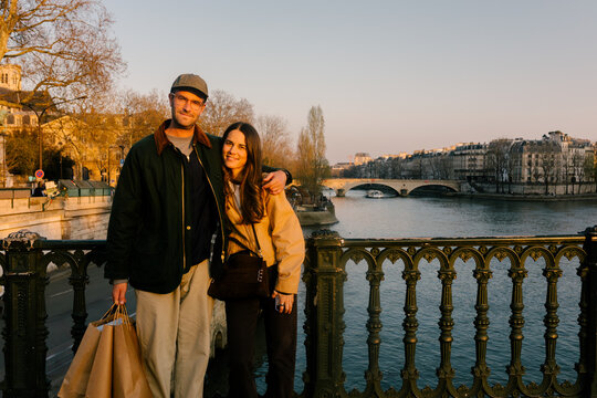 Medium portrait of a smiling couple standing over the Siene River