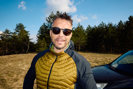 Casual man stands outdoors, smiling at the camera